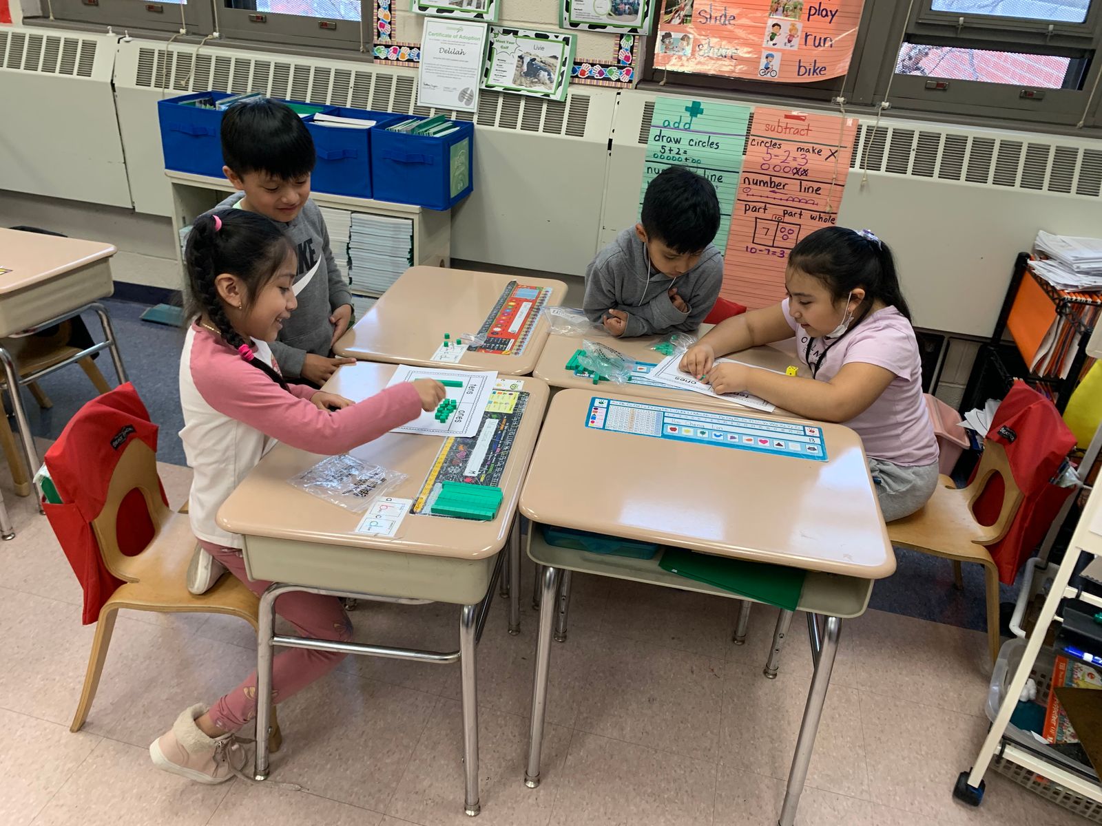 Students at their desks using green base-ten blocks to practice tens and ones