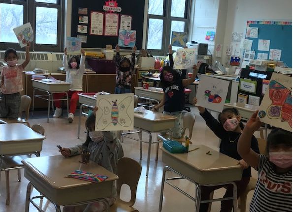 Students in the art room holding up their finished artwork