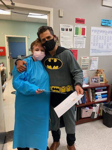 Principal in a Batman costume with a staff member in a blue gown