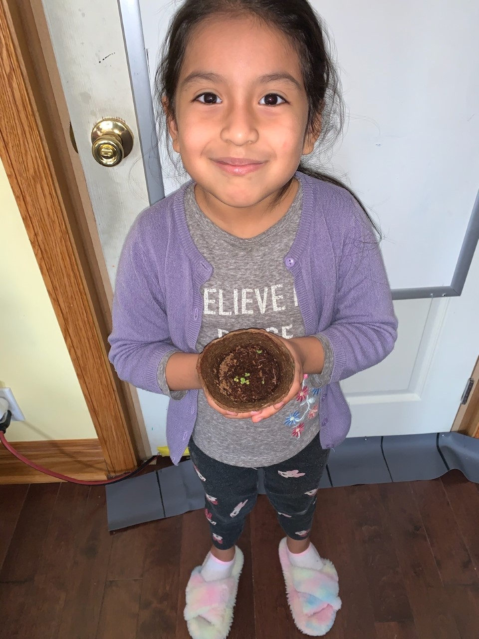 Student in a purple sweater holding a small nest craft