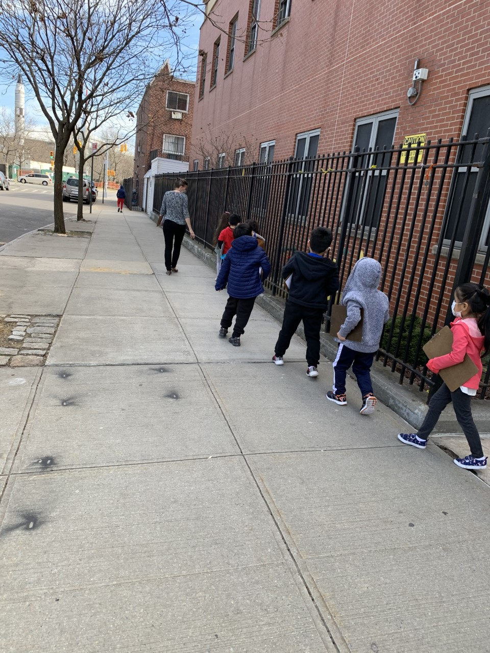 Students walking along the sidewalk beside the school