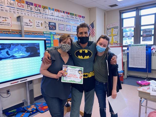 Principal in a Batman costume with two teachers holding a certificate