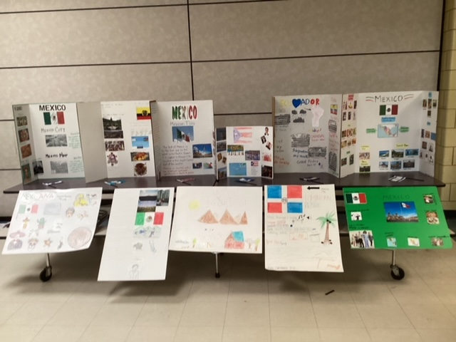 Hand-drawn flag posters displayed below country trifold boards