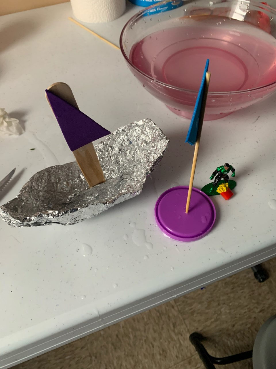 Science experiment with a foil boat, a small flag and a bowl of water
