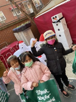 Students holding their green shopping bags beside a snowman decoration