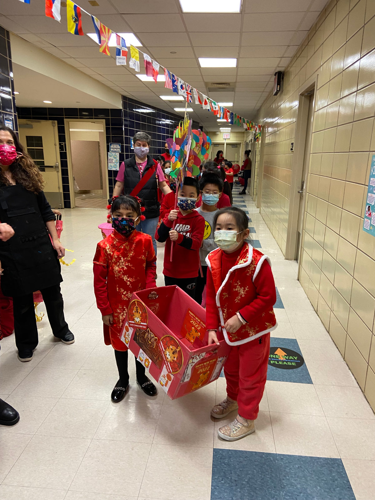 Students in red carrying a paper float in the Lunar New Year hallway parade