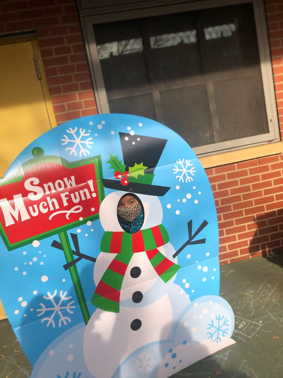 Student peeking through a Snow Much Fun snowman photo board