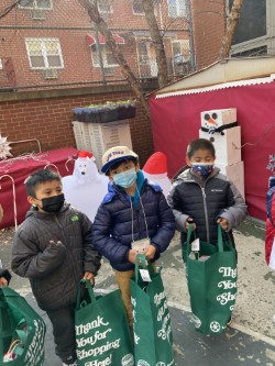 Students with green shopping bags in front of holiday decorations