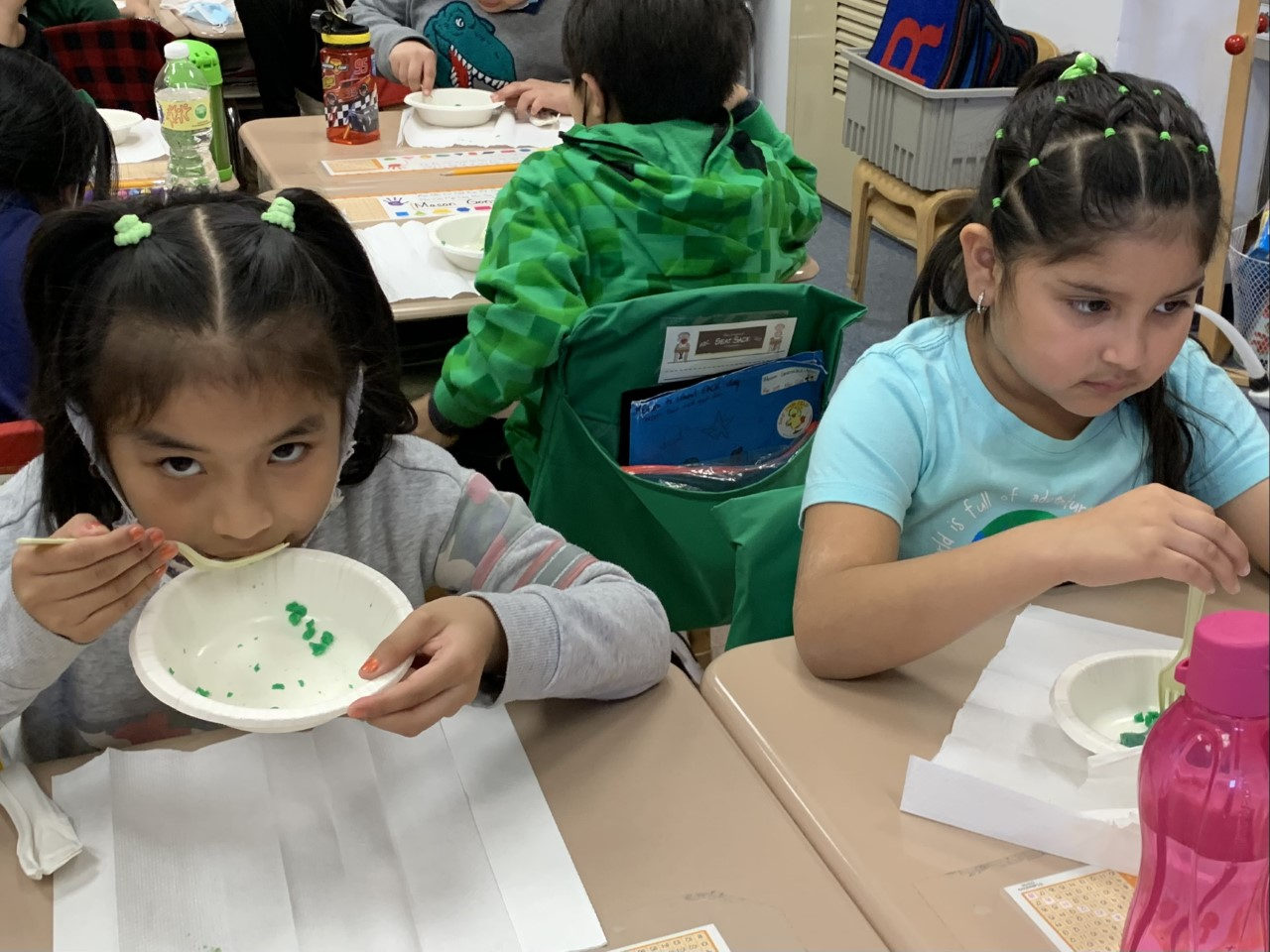 Student eating green eggs from a paper bowl
