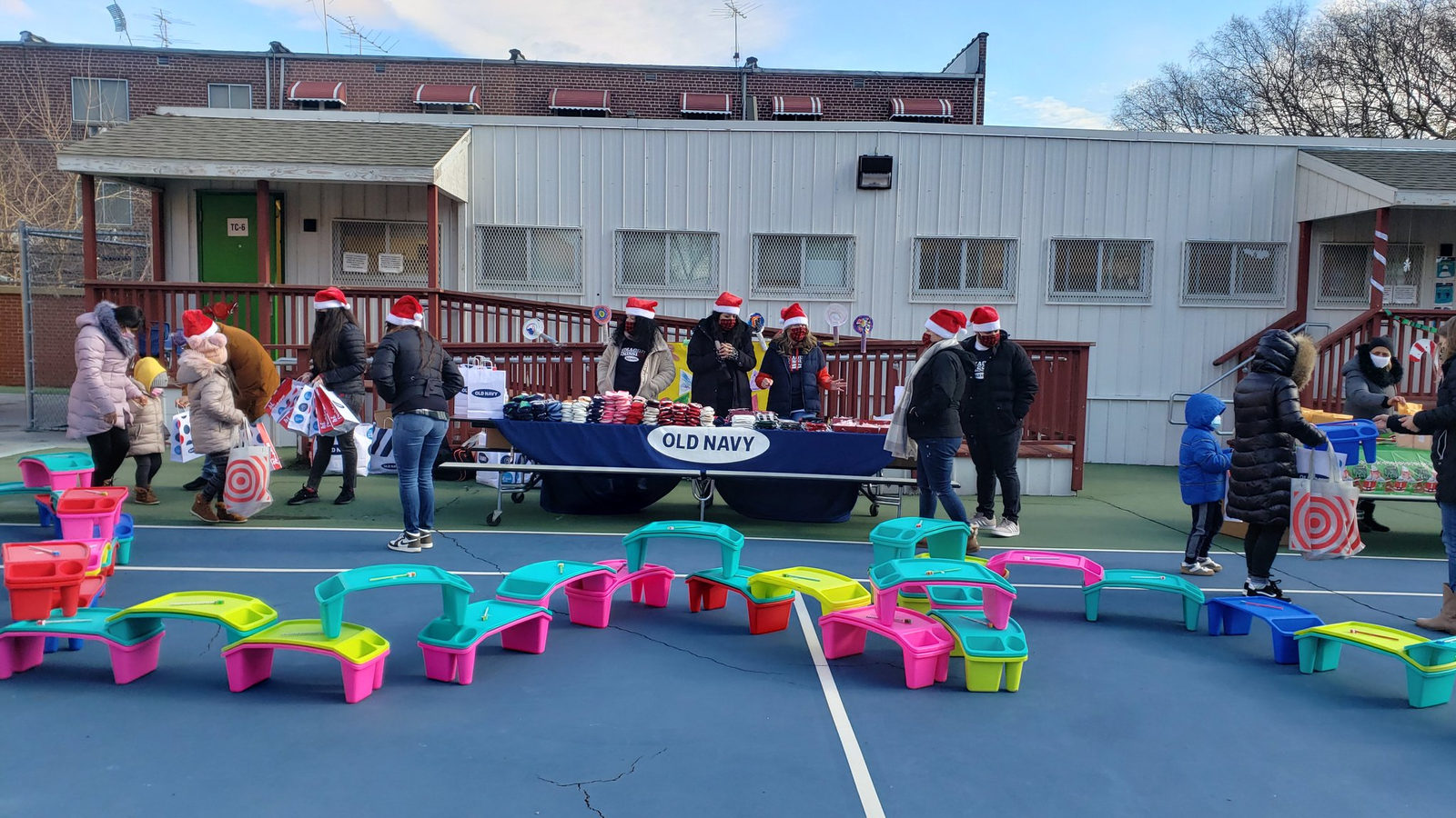 Families and staff in Santa hats at Old Navy tables in the schoolyard