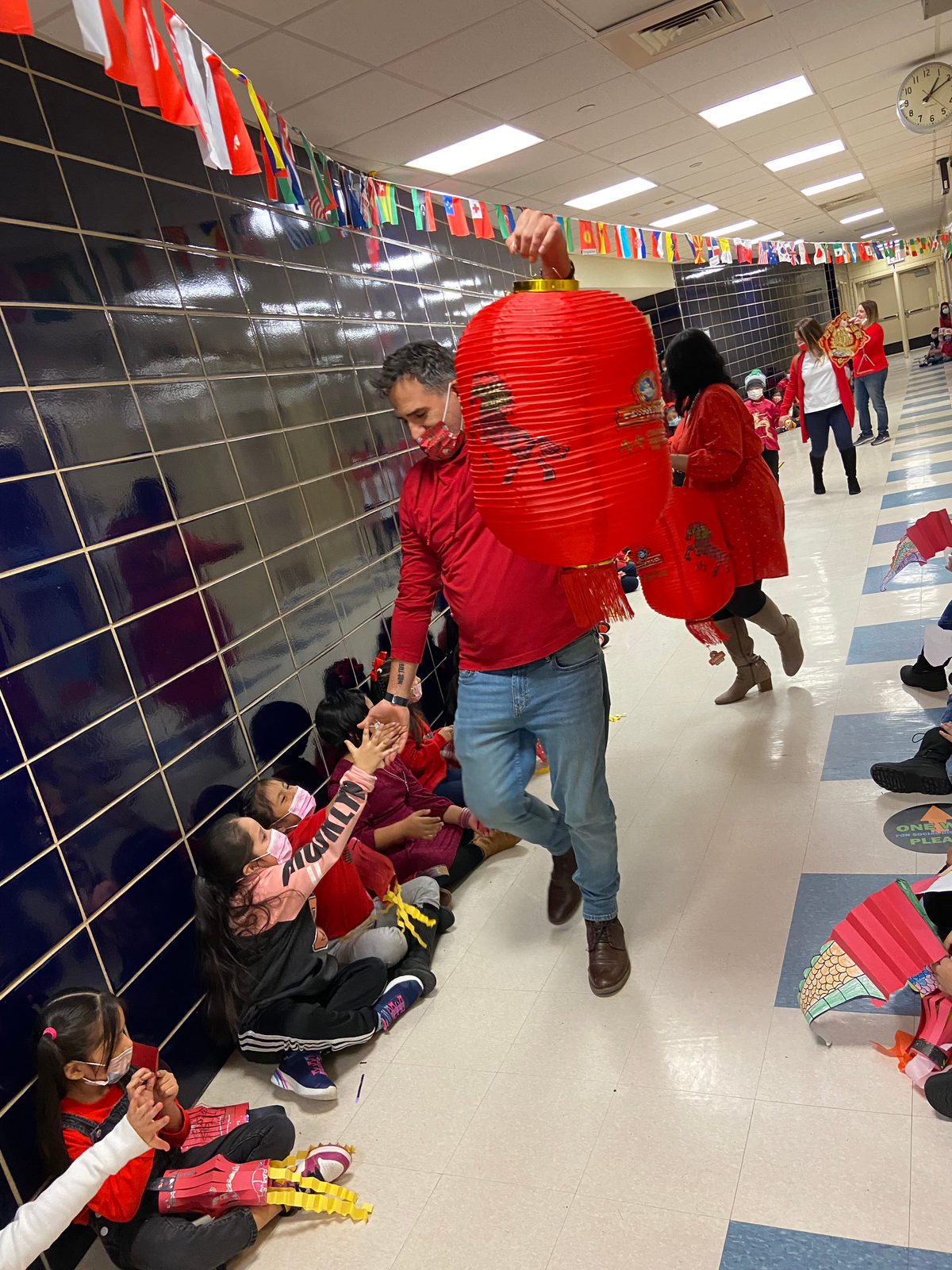 Teacher carrying a red lantern in the Lunar New Year hallway parade