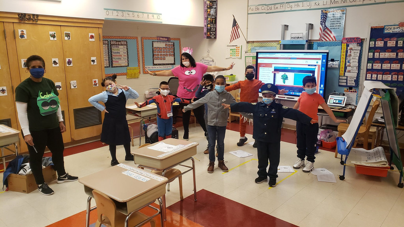 Students in Halloween costumes standing by their desks