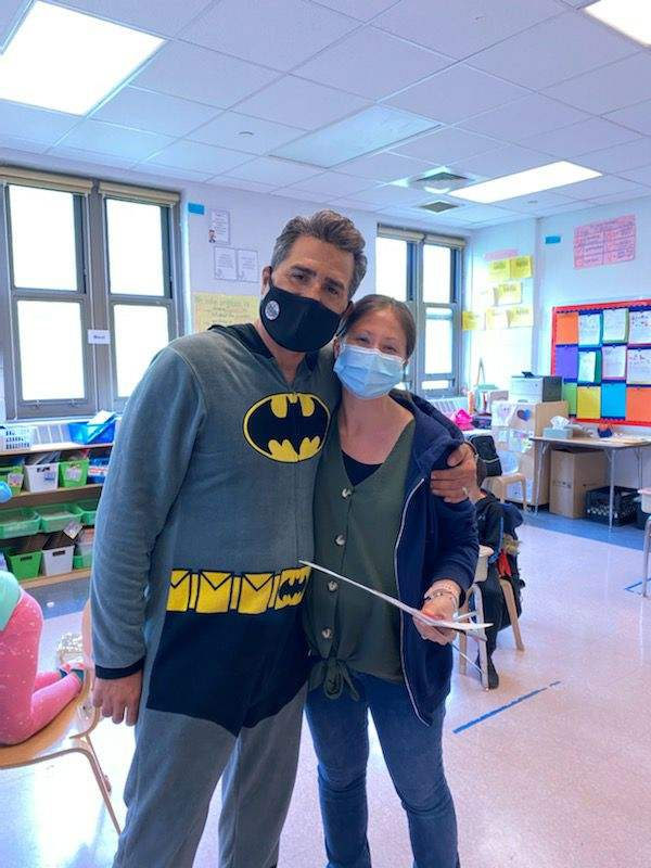 Principal in a Batman costume with a staff member holding a certificate