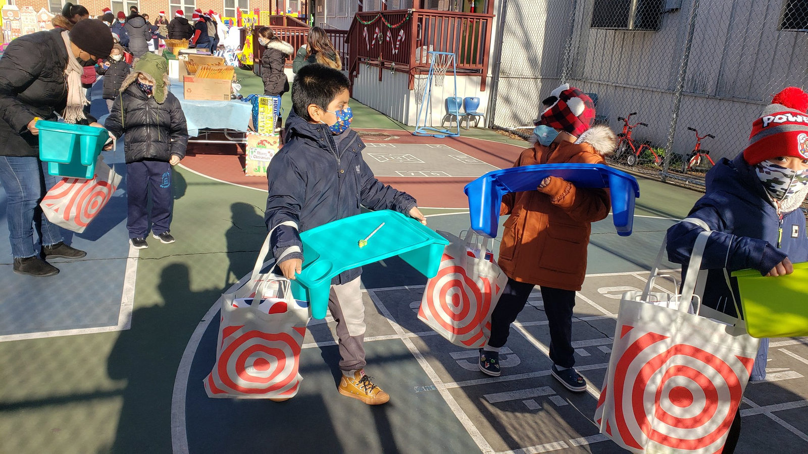 Families carrying gift bags and supplies across the schoolyard