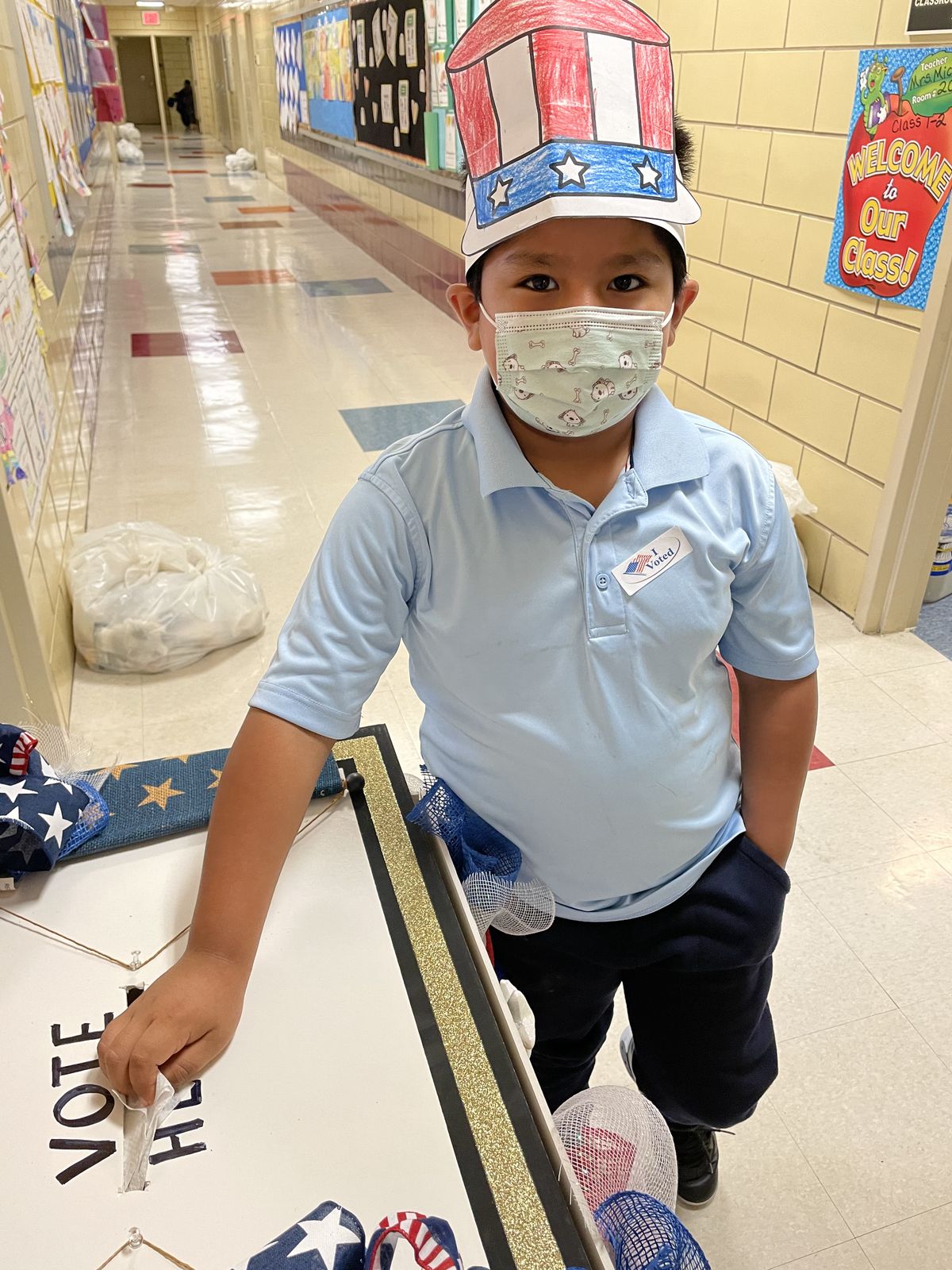 Student in a paper Uncle Sam hat voting at the ballot box