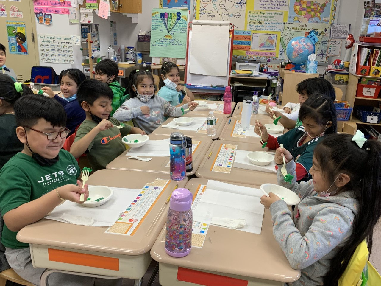 Students at their desks eating green eggs