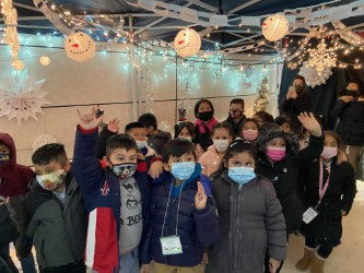 Students waving inside a tent decorated with lights and snowflakes