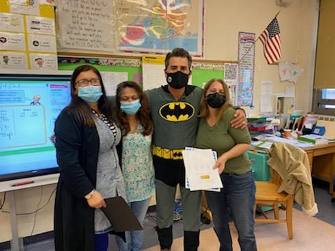 Principal in a Batman costume with teachers in a classroom