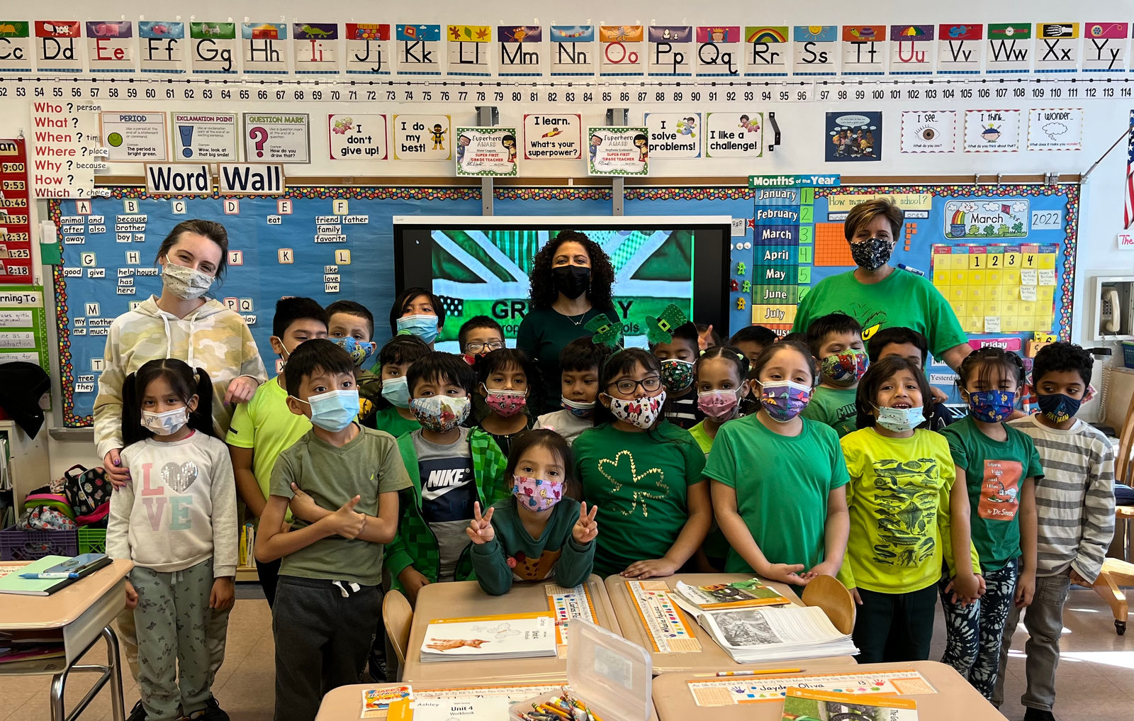 Class dressed in green posing in front of the word wall