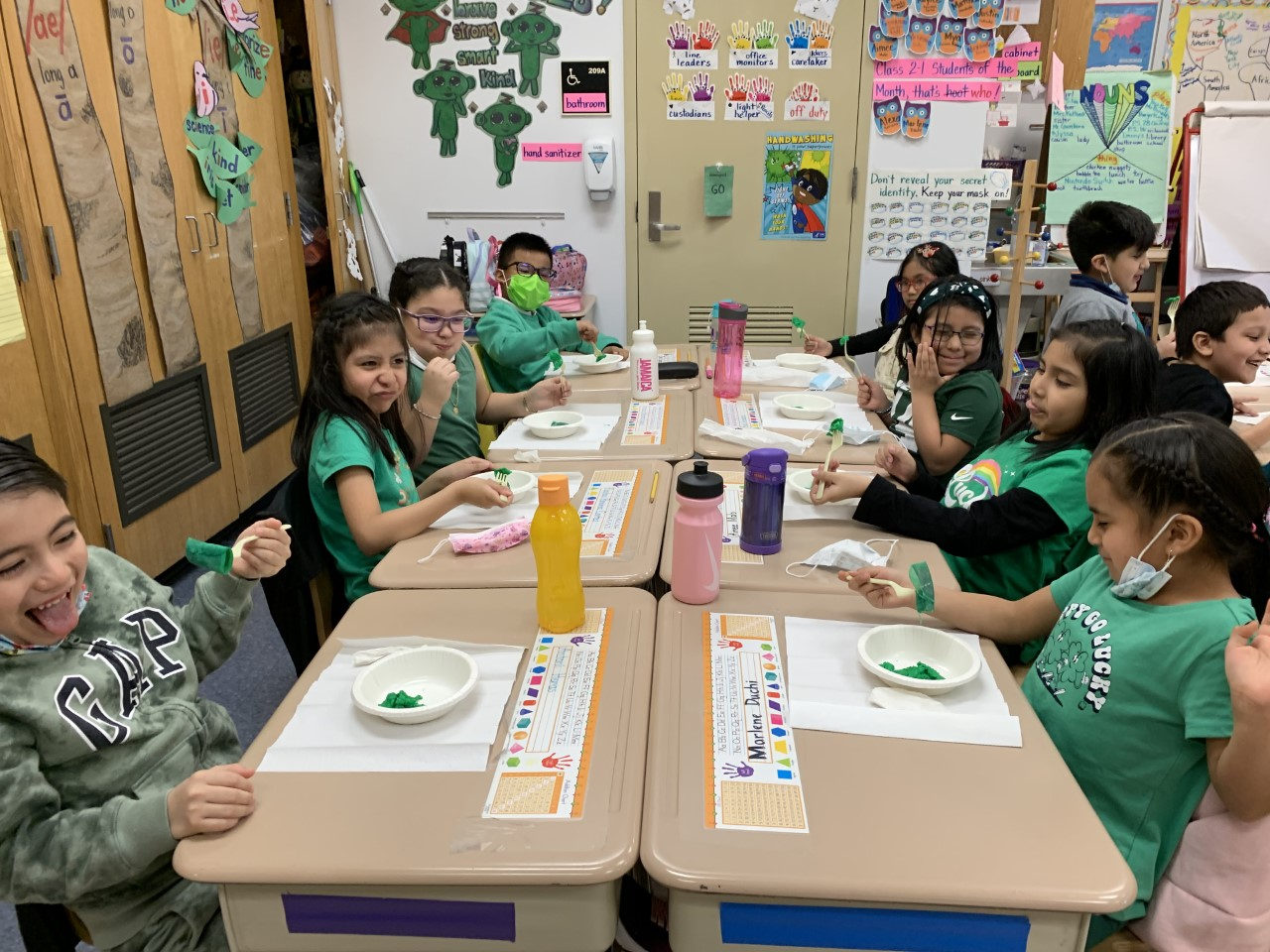 Students dressed in green eating at their desks