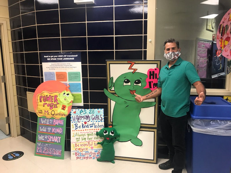 Staff member with Z, a green character, beside anti-bullying posters