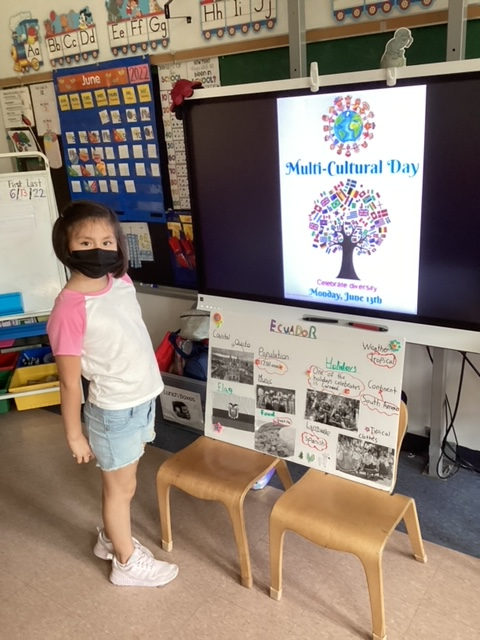 Student in a mask standing beside a country project poster