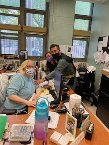 Principal in a Batman costume visiting office staff at their desks