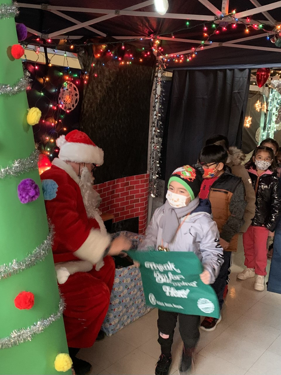 Santa handing a student a green gift bag