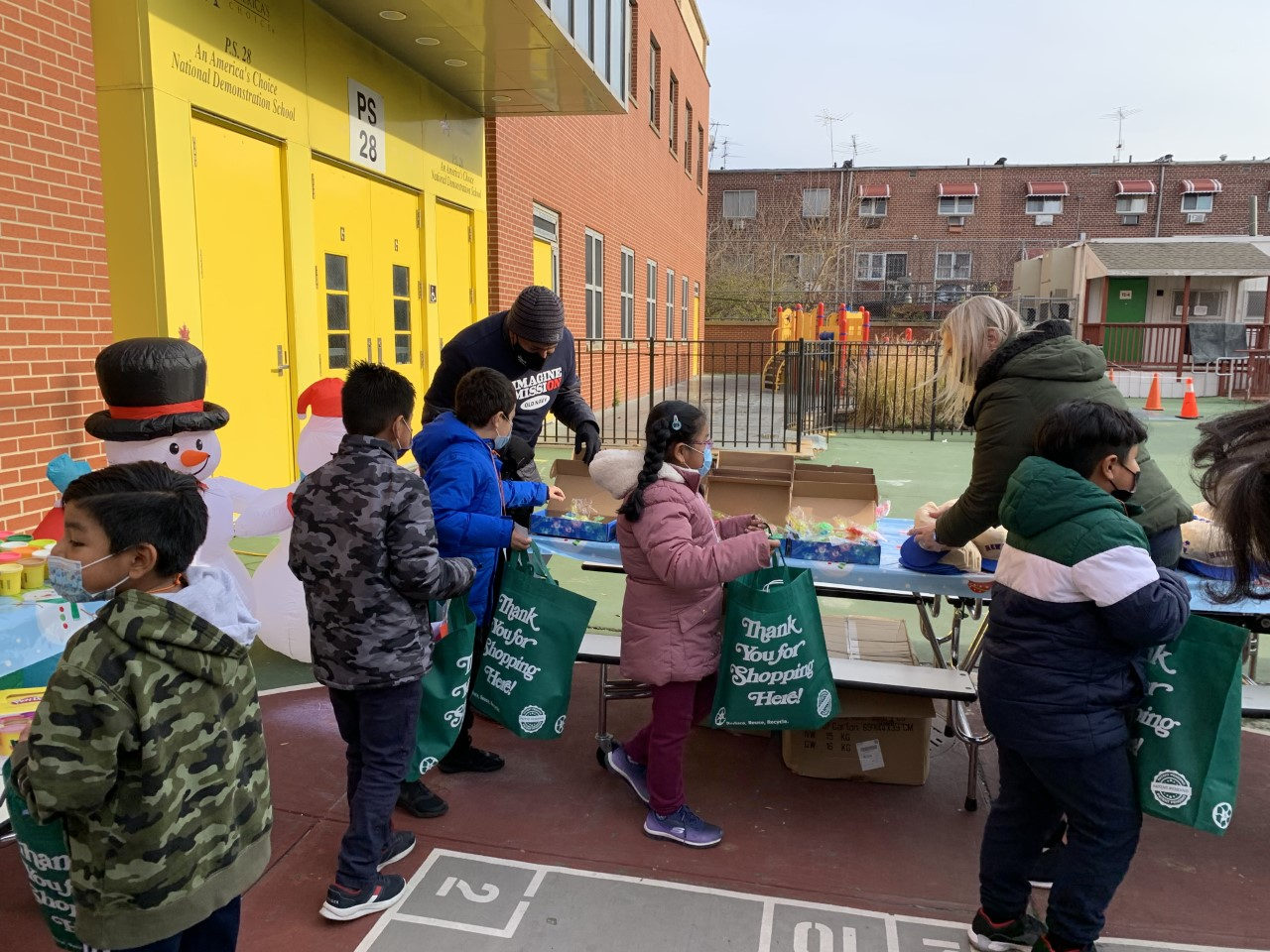 Students collecting gift bags at a table in the schoolyard