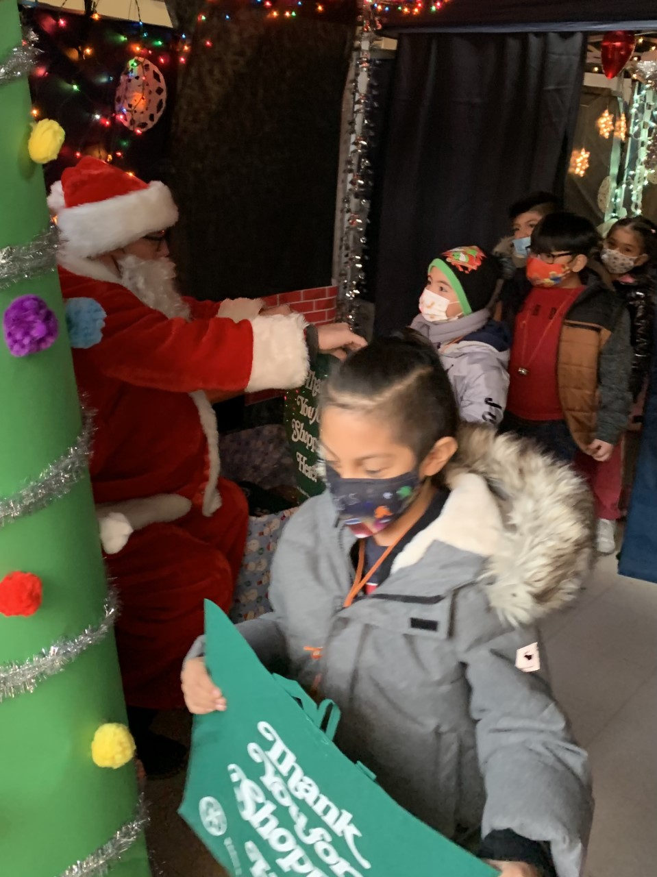 Santa greeting a student holding a green gift bag