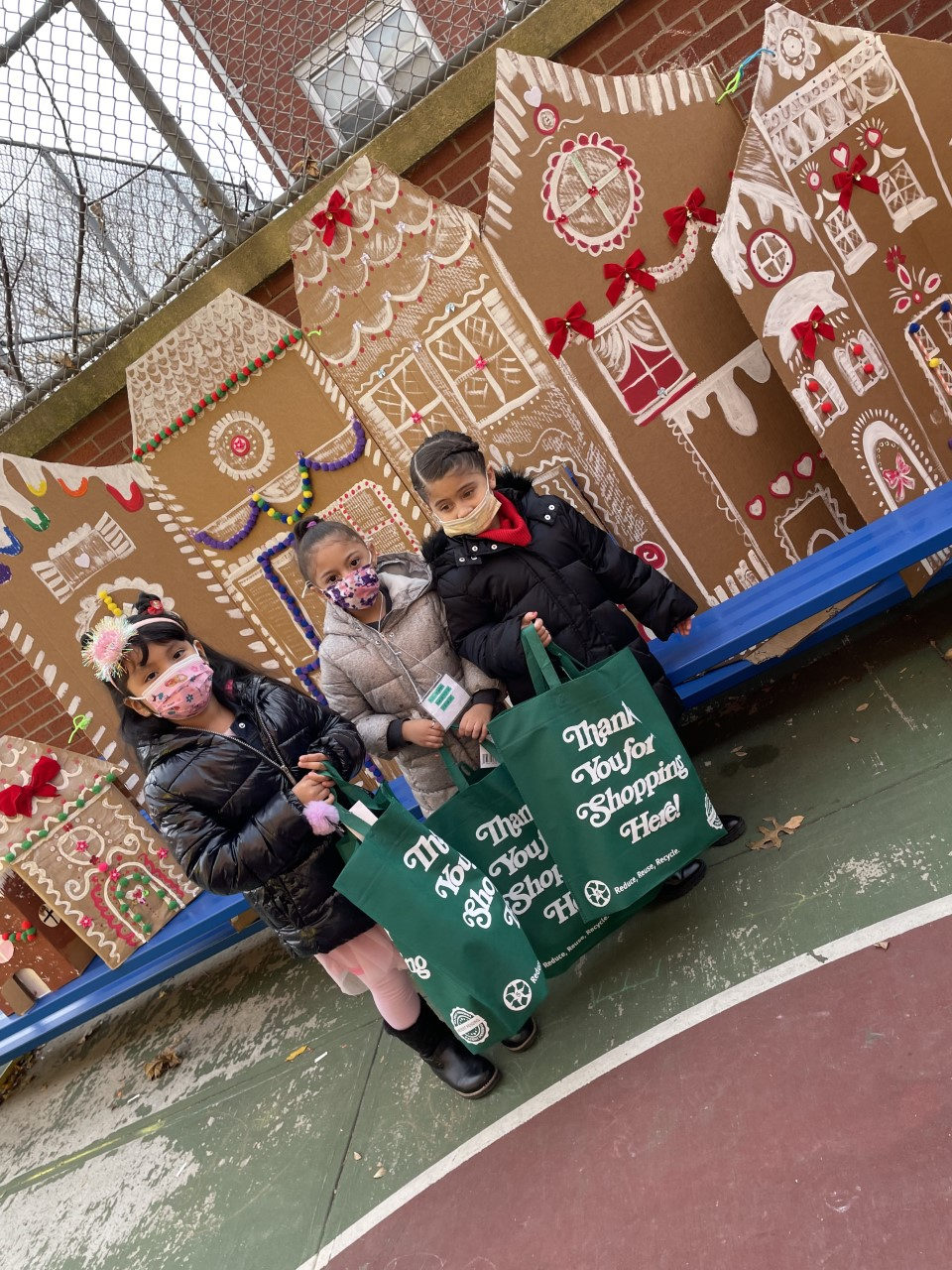 Students with gift bags in front of a gingerbread house display
