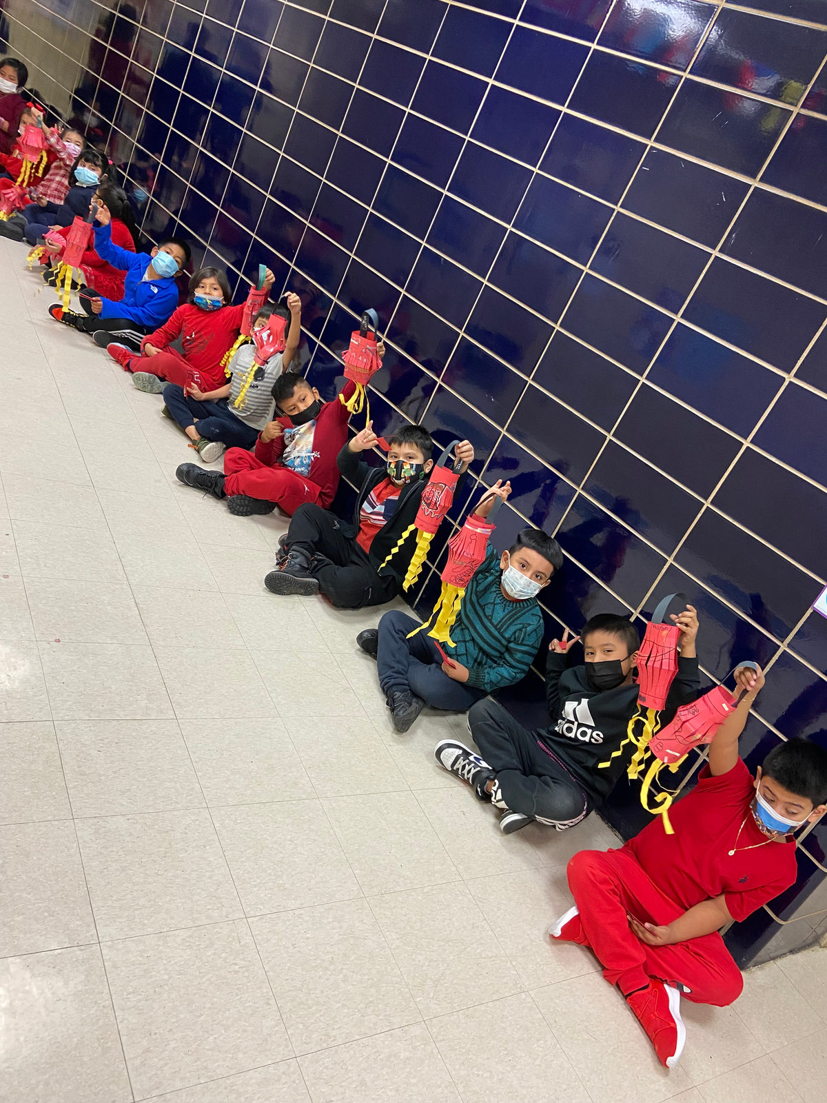 Students lined up along the hallway holding paper dragons for Lunar New Year