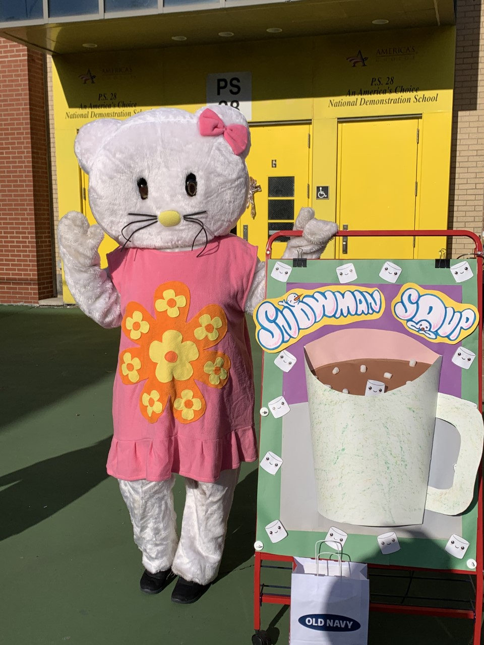 Costumed Hello Kitty character waving beside a Snowman Soup display