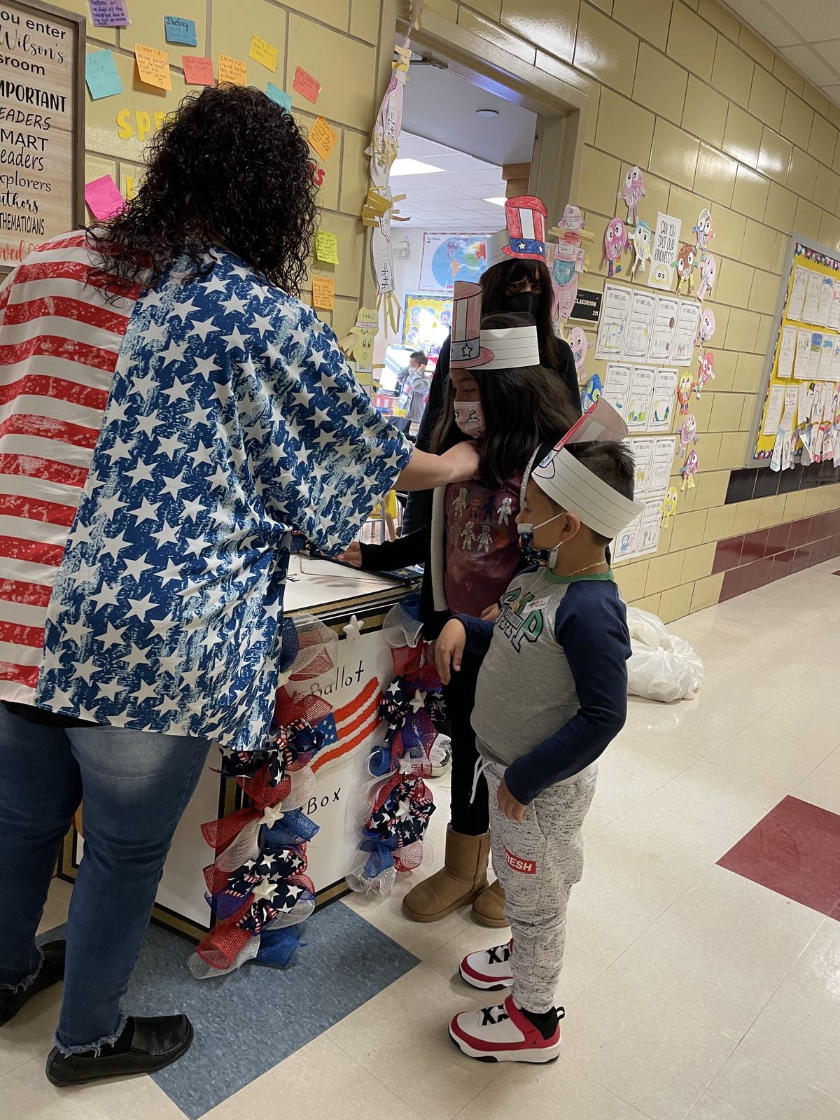 Teacher helping students cast their votes at the ballot box