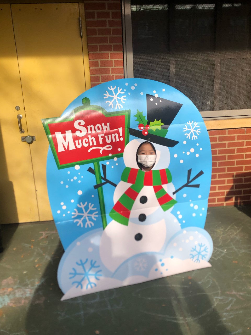 Student posing in a Snow Much Fun snowman photo board