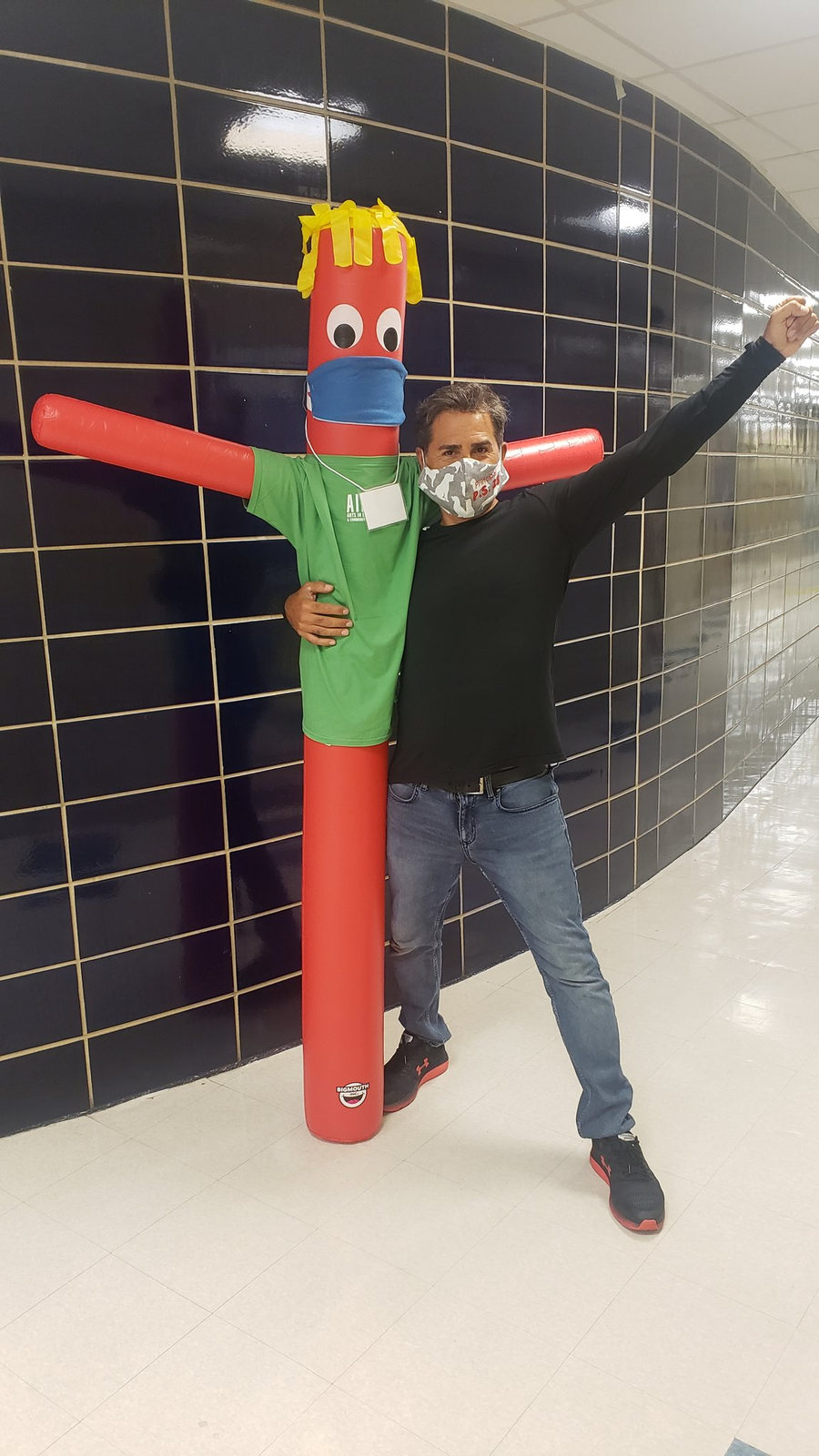 Staff member posing with an inflatable tube dancer in the hallway