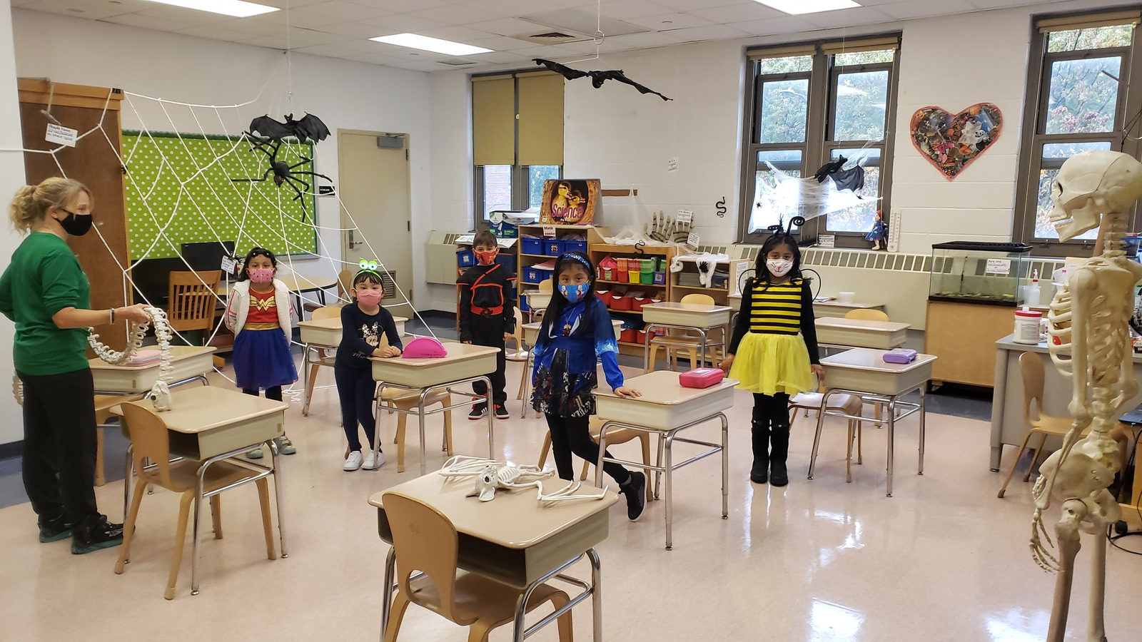 Students in costumes including a bumblebee standing by their desks