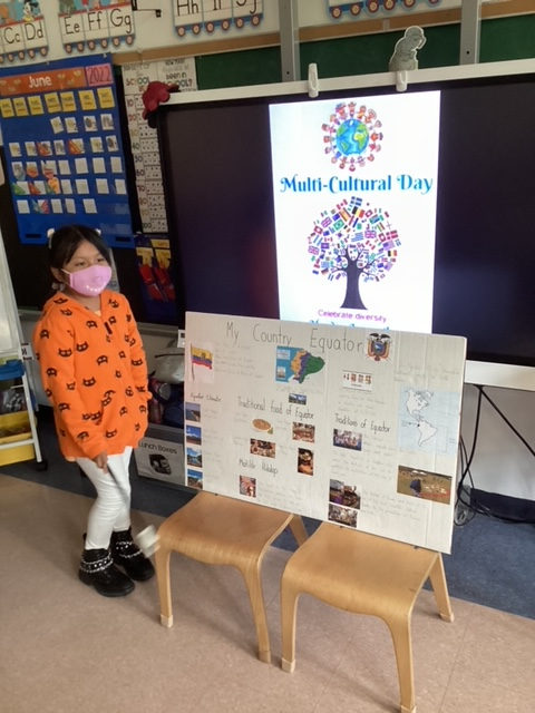 Student in an orange jacket beside a country project poster