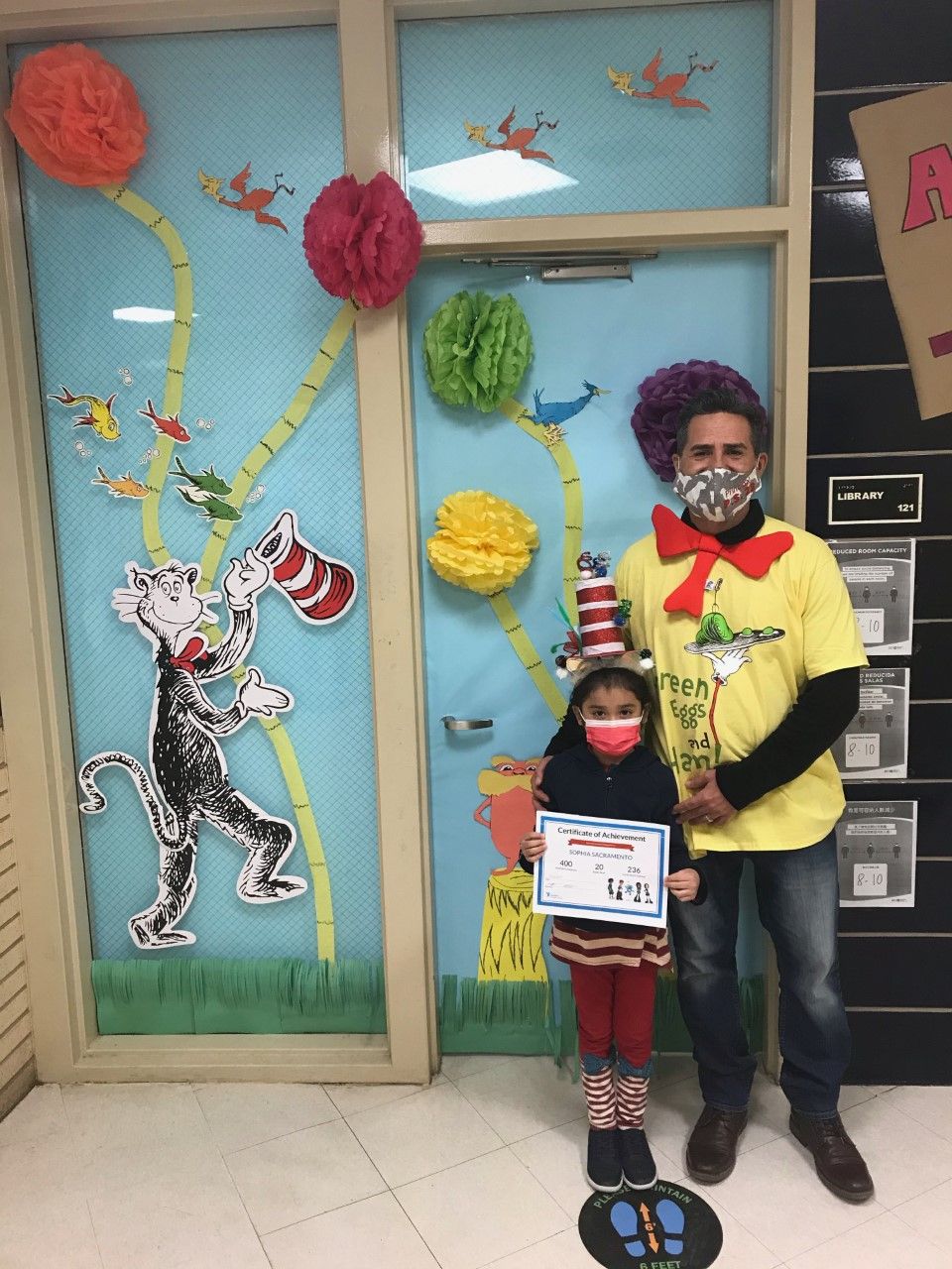 Staff member in a Cat in the Hat hat with a student holding a certificate