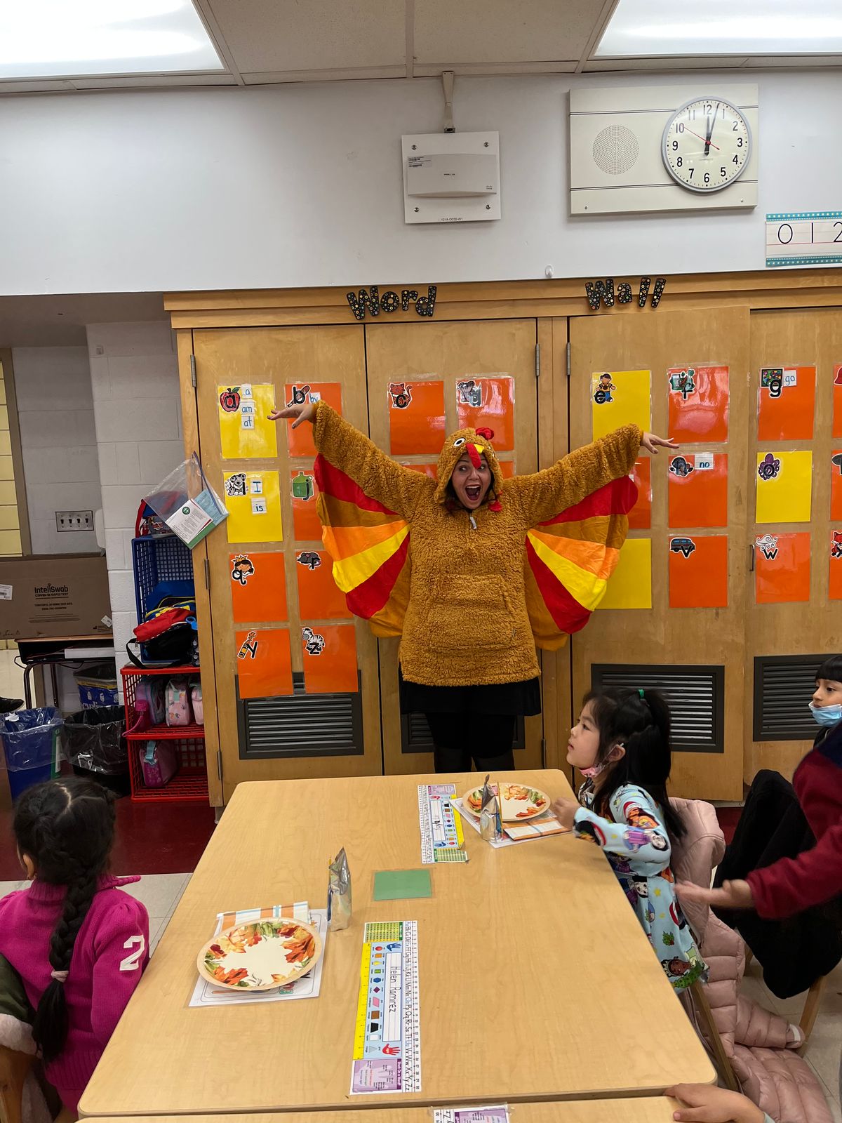 Teacher in a turkey costume spreading her wings in a classroom