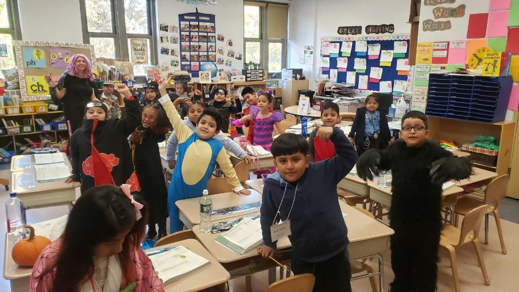Students in costumes including a dinosaur in their classroom