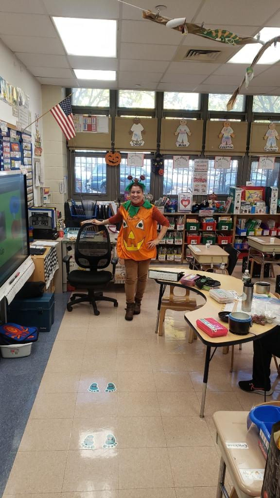 Staff member in a pumpkin costume in a classroom