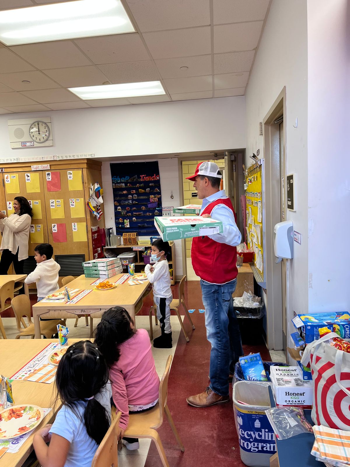 Visitor in a red vest handing out boxes to students at their tables