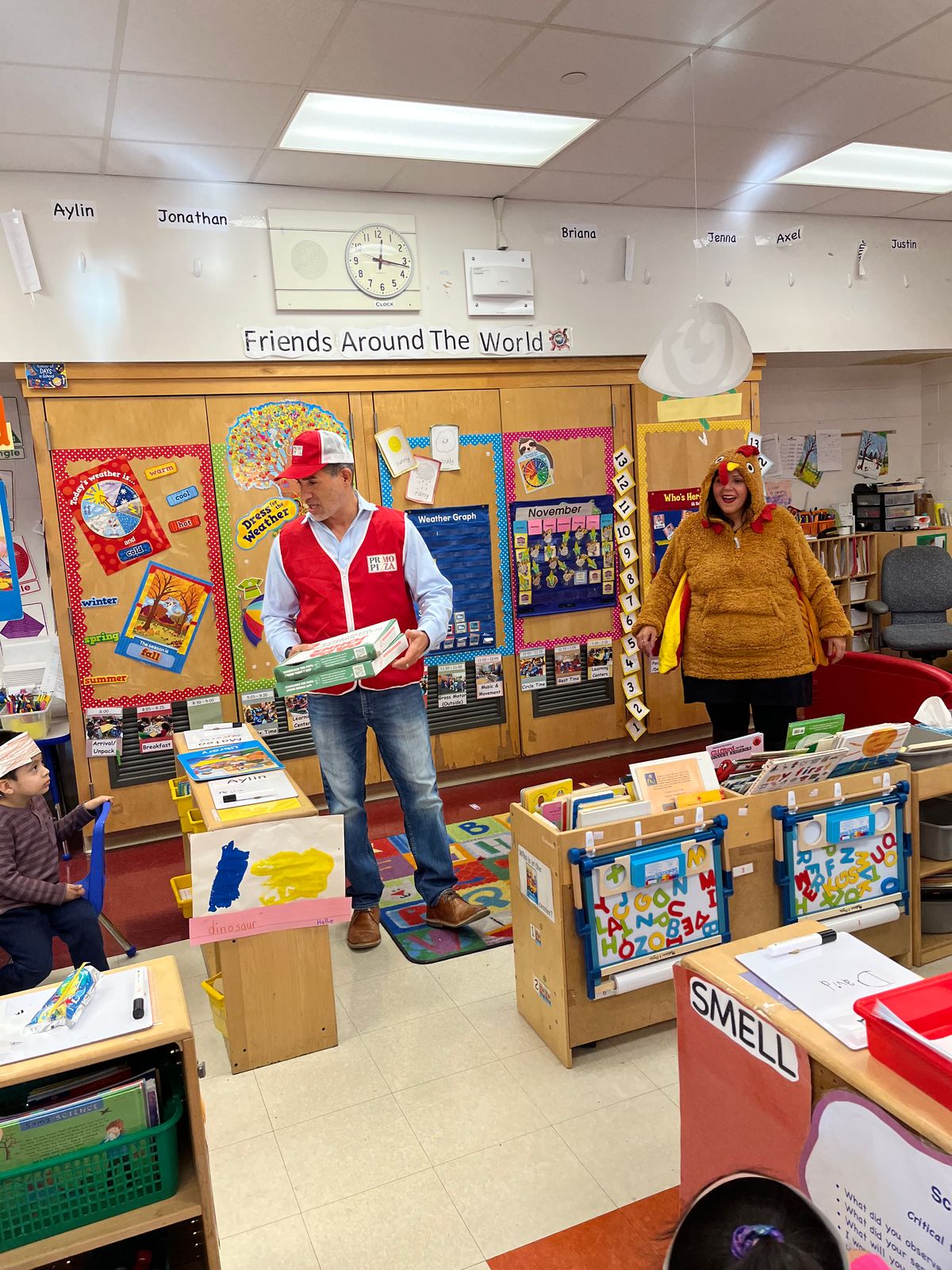 Visitors in red vests handing out boxes as a teacher in a turkey costume looks on