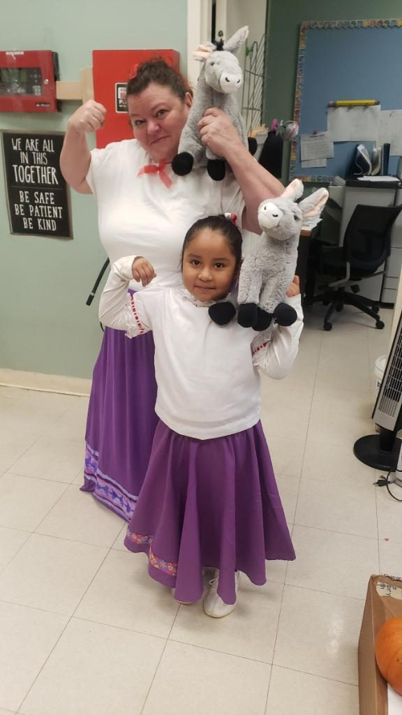 Teacher and student in matching costumes holding stuffed llamas