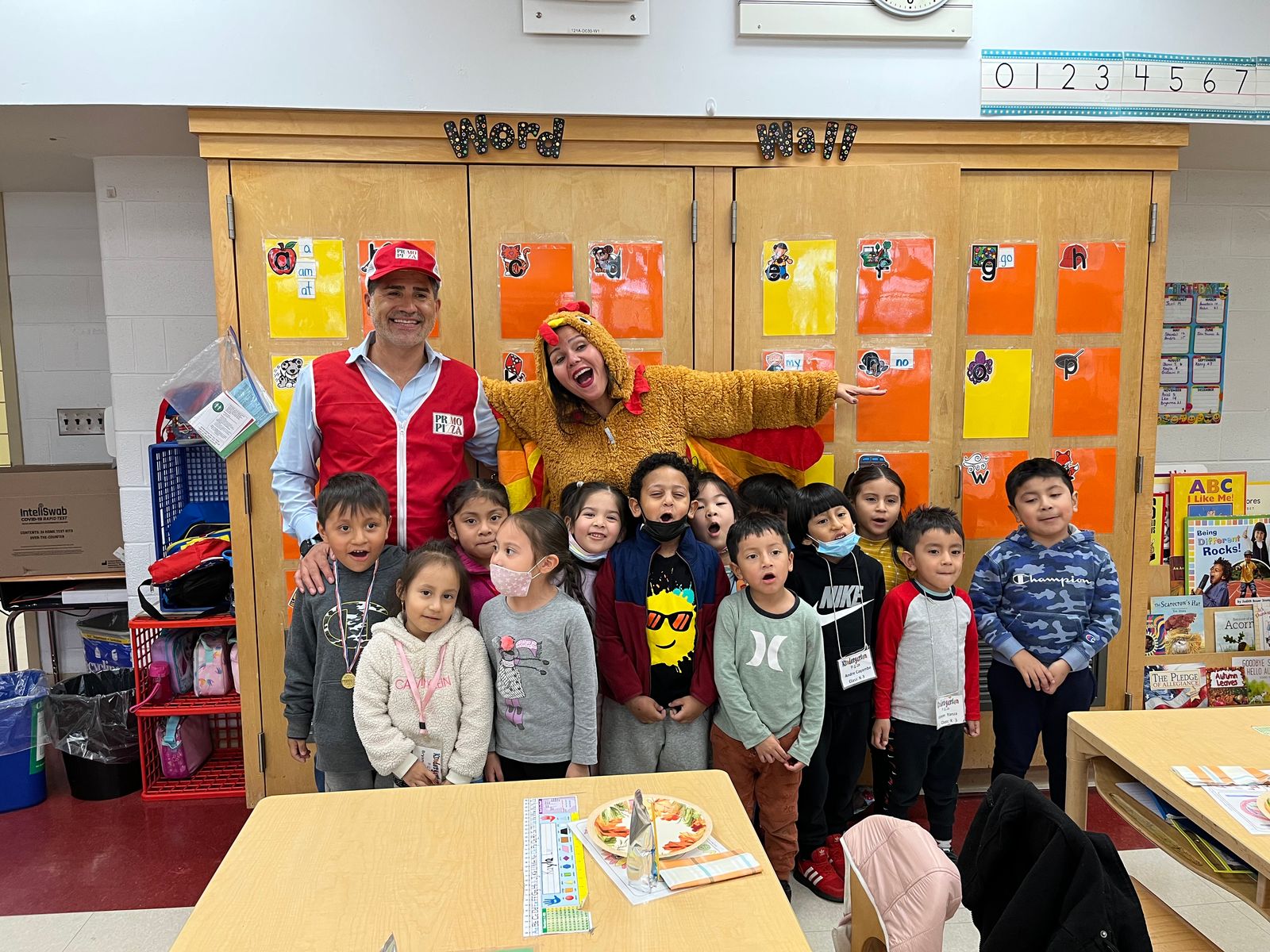 Visitors in red vests and a teacher in a turkey costume with a class