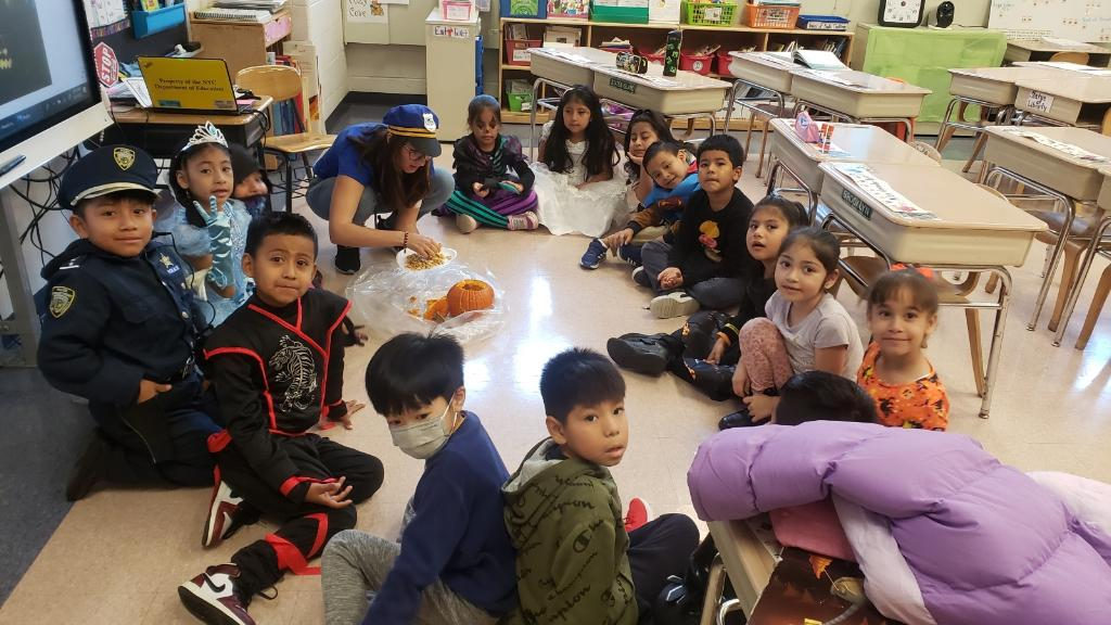 Students in costumes sitting on the classroom floor