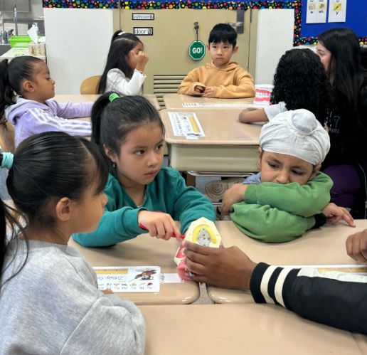 Students at their desks holding a tooth model during a dental health lesson