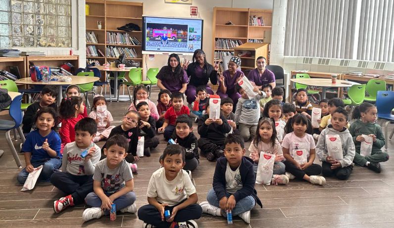 Class seated on the floor with their dental goodie bags
