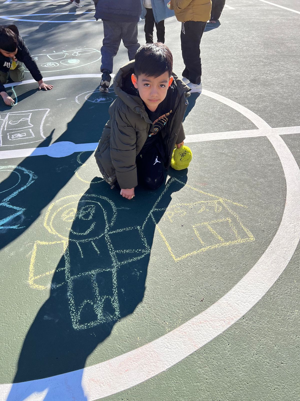 Student drawing with chalk on the schoolyard blacktop